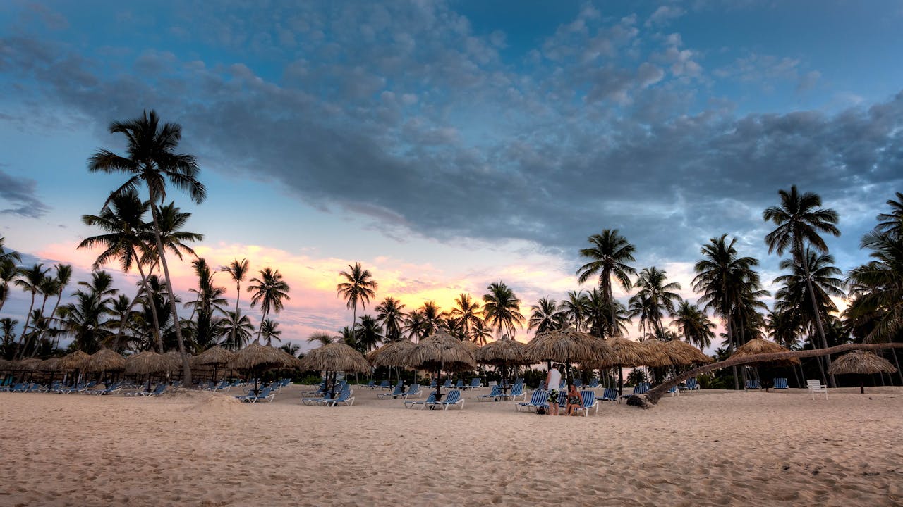 Idyllic tropical beach with palm trees at sunset in Bávaro, perfect for relaxation and vacation.